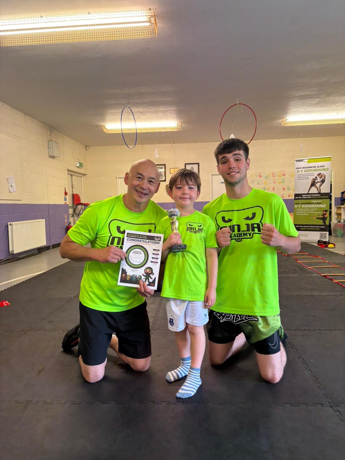 Student receiving trophy and belt certificate at Little Ninjas presentation